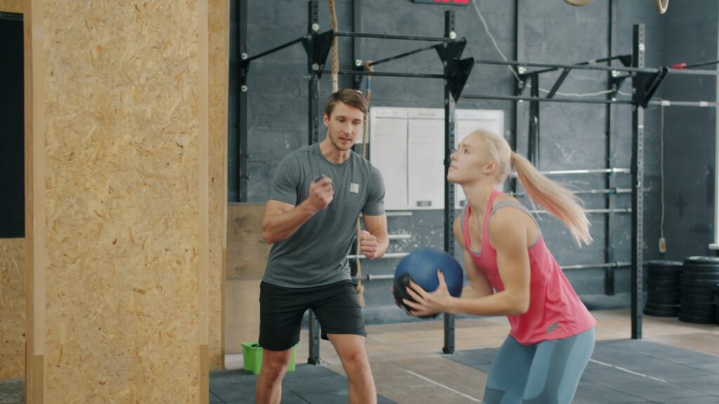 Fitness instructeur begeleidt sporter met medicine ball tijdens functionele training in de gym